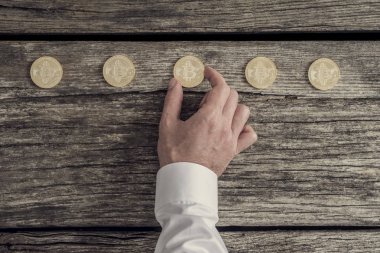İşadamı Beyaz gömlekli beş altın bitcoins üst üste yerleştirerek