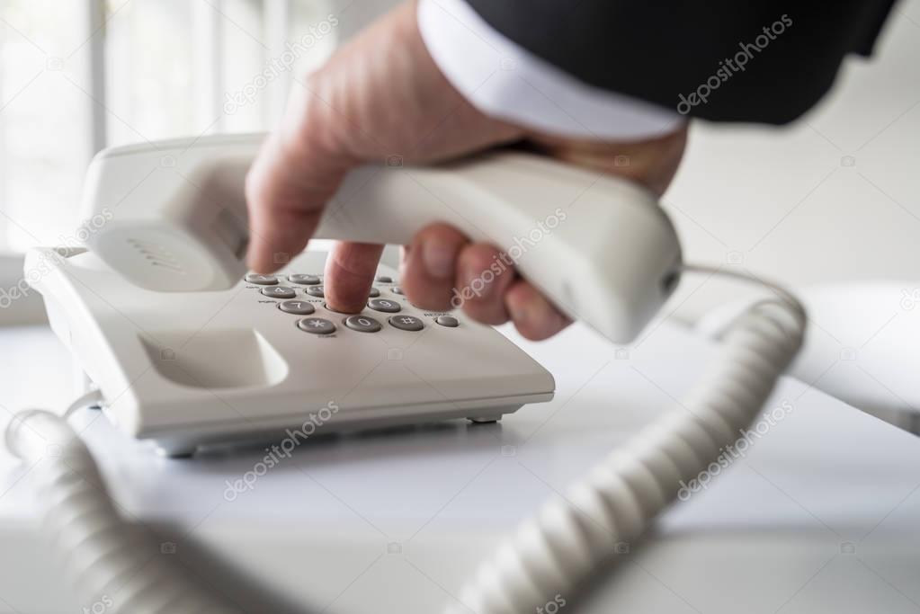 Businessman dialing a telephone number