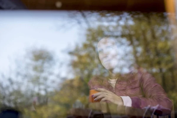 Reflejos de árboles sobre vidrio con una mujer detrás — Foto de Stock