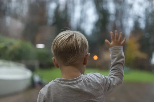 Anak kecil berdiri menatap keluar jendela — Stok Foto