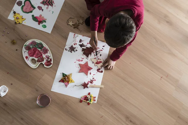 Uma criança fazendo decorações de pintura de Natal — Fotografia de Stock