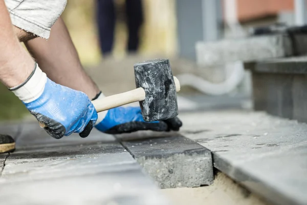 Operaio posa di una pavimentazione in pietra o mattoni — Foto Stock