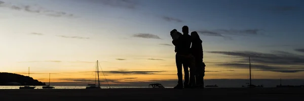 Вид ззаду сімейства силуетів на відкритому повітрі, обіймаючись, дивлячись на — стокове фото