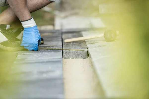 Builder measuring a gap for a new paving stone — Stock Photo, Image