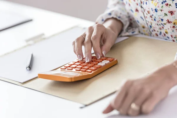 Businesswoman using orange calculator in the office