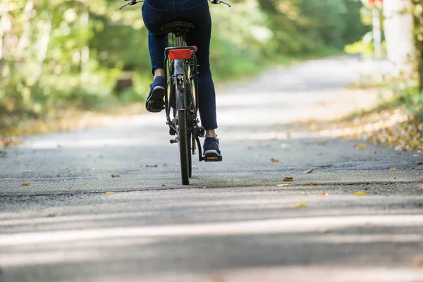 Arka görünümü bir bisiklet sürme bir kadının kırpılmış — Stok fotoğraf