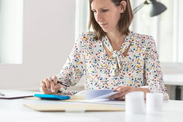 Female accountant doing a calculation on a blue manual calculato — Stock Photo, Image