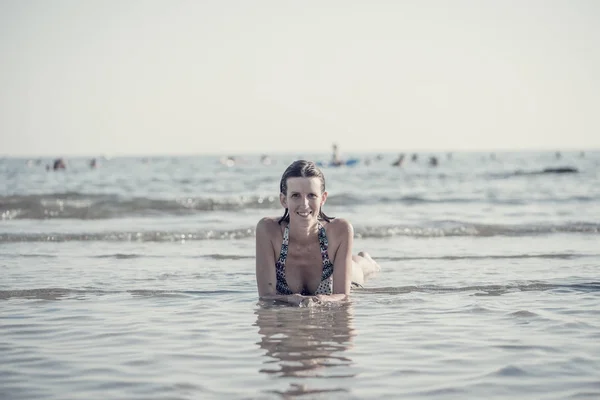 Framsida av en leende kvinna med blött hår iklädd baddräkt ligg — Stockfoto