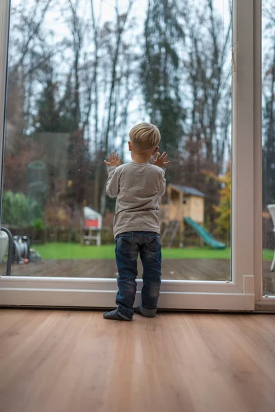 Одинокий ребенок, стоящий на деревянном полу дома перед домом. — стоковое фото