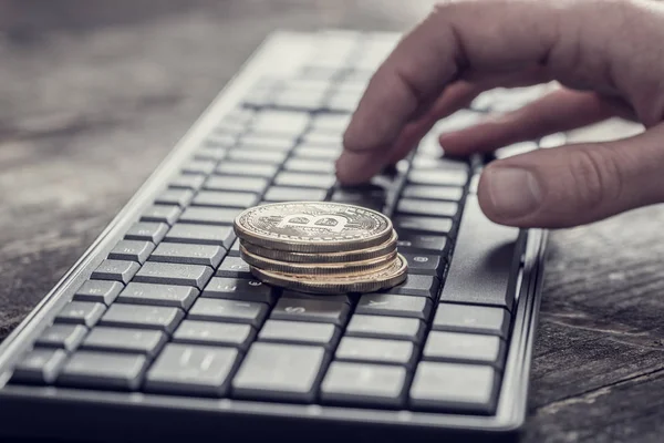 Bitcoin oro sobre el teclado de la computadora negro y el dedo masculino — Foto de Stock