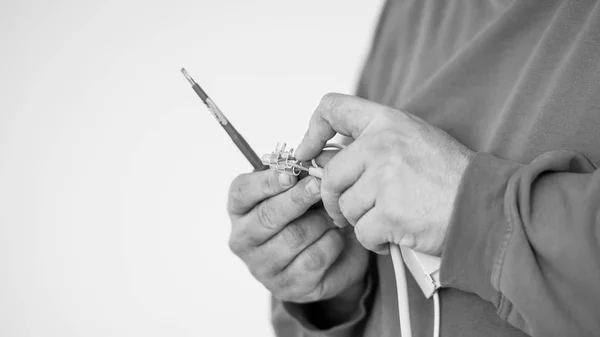 Greyscale image of a handyman checking a connector and an electr — Stock Photo, Image