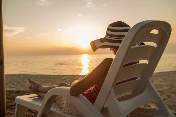Mujer relajándose en un sillón reclinable en la playa — Foto de Stock