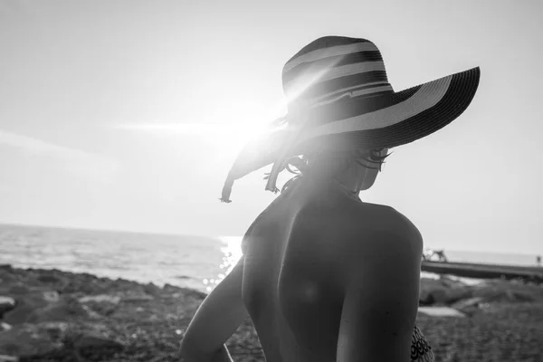 Монохромне зображення жінки на пляжі, спостерігаючи за заходом сонця через оазу — стокове фото