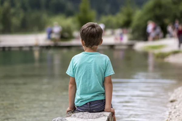Anak muda duduk di tepi danau — Stok Foto