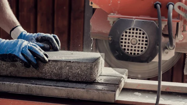 Workman usando um moedor de ângulo para cortar um bloco de concreto em um lado — Fotografia de Stock