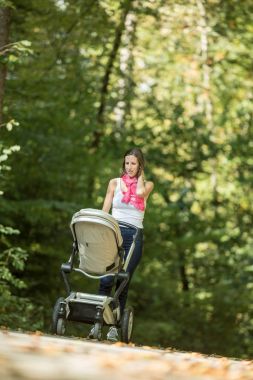 Anne çocuk arabası veya kırsal yol throug boyunca bebek arabası itme