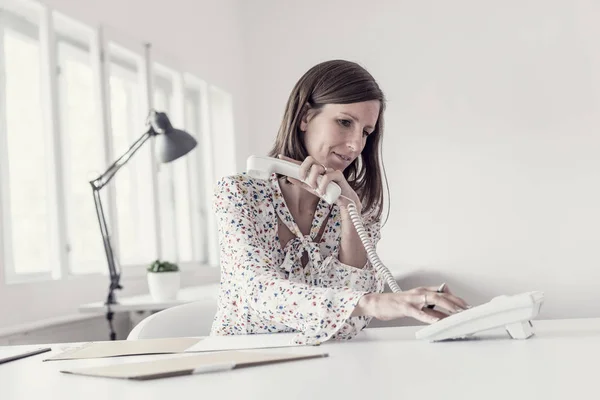 Giovane donna d'affari seduta alla scrivania del suo ufficio a fare un telefono — Foto Stock