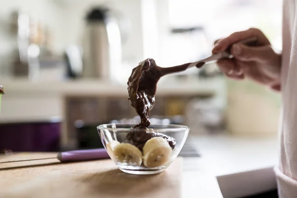 Woman spooning chocolate sauce onto a dessert — Stock Photo, Image