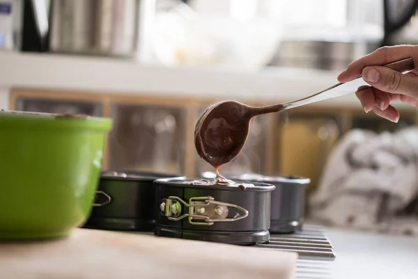 Mujer llenando latas para hornear con mezcla de pastel de chocolate —  Fotos de Stock