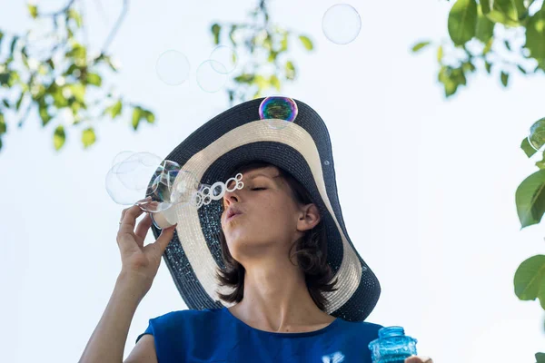 Привлекательная женщина в широком полыхающем солнцезащитном халате, пускающая пузыри — стоковое фото