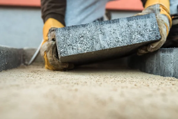 Construtor que estabelece um tijolo de pavimentação colocando-o sobre a fundação de areia — Fotografia de Stock