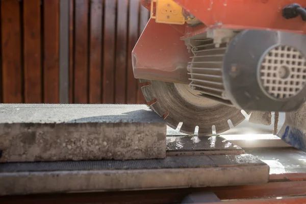 An angle grinder or circular saw with a concrete block