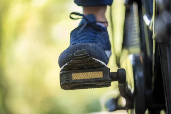 The foot of a person riding a bike outdoors