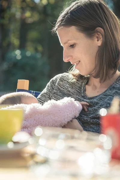 Joven madre amamantando a su pequeño bebé en sus brazos como rel — Foto de Stock