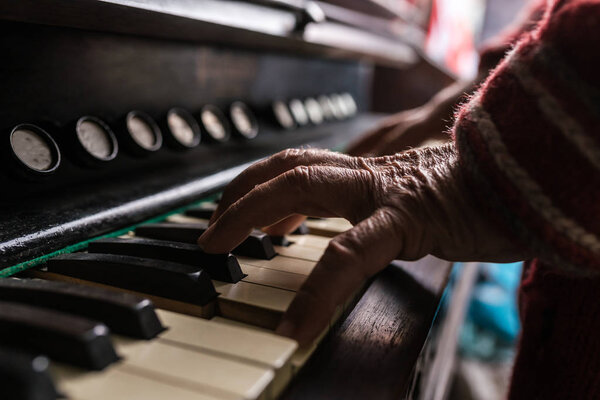 Old man playing the piano in a close up view of his wrinkled han
