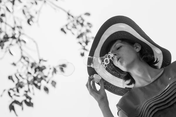 Yksivärinen kuva naisen hattu puhaltaa kuplia — kuvapankkivalokuva