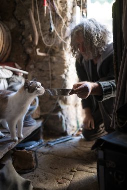 Ca besleme yerde diz çökmüş dağınık uzun gri saçlı adam