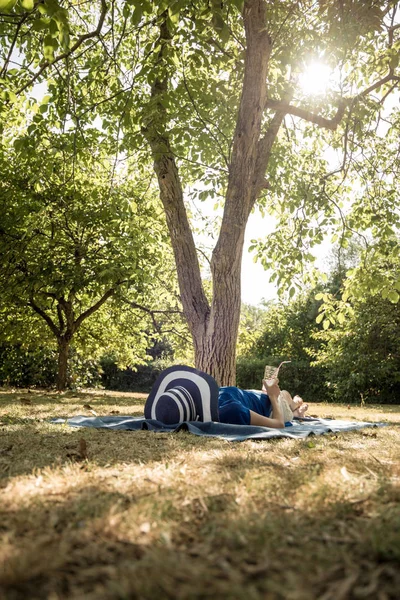 Γυναίκα ξαπλωμένη χαλαρώνοντας στον πίσω κήπο της — Φωτογραφία Αρχείου