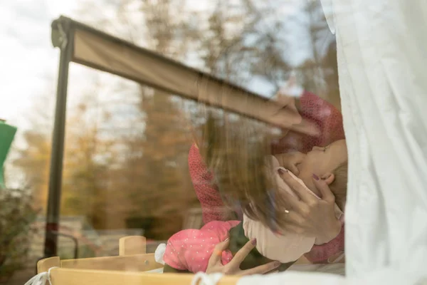 Madre en jersey rosa sosteniendo a una niña dentro de casa — Foto de Stock
