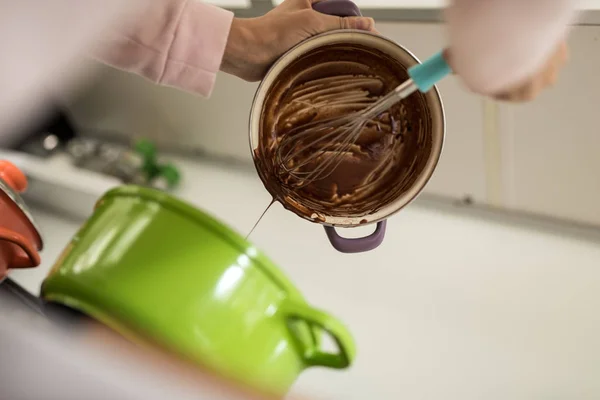 Cozinhe esvaziando o molho de chocolate de uma panela — Fotografia de Stock