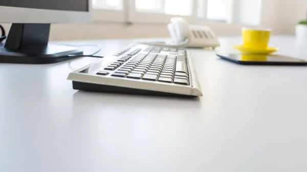 Tastiera e computer desktop su un tavolo da ufficio bianco — Foto Stock