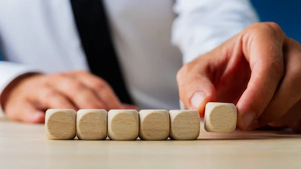 Empresario colocando seis dados de madera en blanco en una fila — Foto de Stock