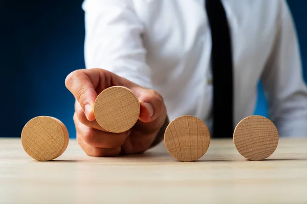 Podnikatel umísťuje čtyři prázdné dřevěné řezné kruhy do řady — Stock fotografie