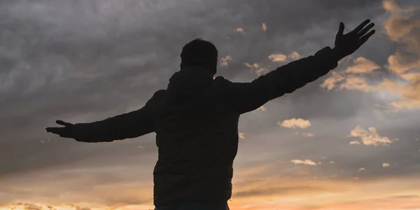 Homem de pé com os braços bem abertos sob um céu vespertino — Fotografia de Stock