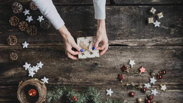 Top view of female hand tying o golden bow on top of holiday gif — Stock Photo, Image