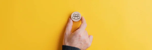 Main masculine plaçant cercle de coupe en bois avec le symbole de personnes sur elle — Photo