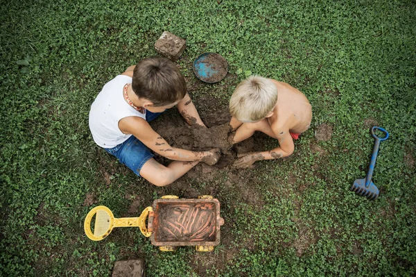 Top view of two brothers sitting on  grass playing with mud — Stock Photo, Image