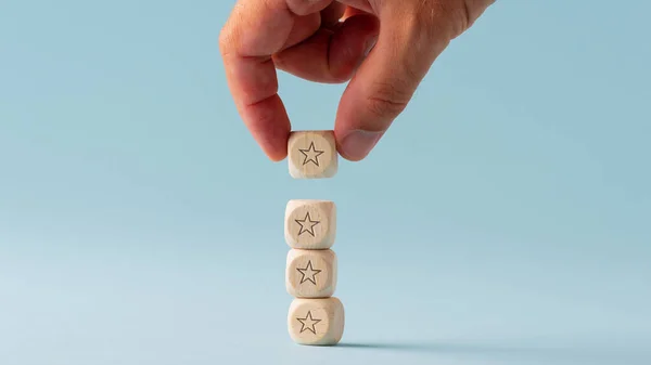 Mão masculina empilhando cinco dados de madeira com forma de estrela sobre eles — Fotografia de Stock