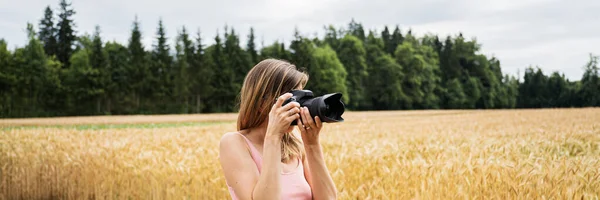 Junge Frau mit professioneller DSLR-Kamera, die draußen Fotos macht — Stockfoto