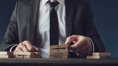 İş adamı birlikte daha güçlüyüz işareti yapıyor.