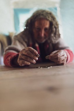 Kıvırcık saçlı, yırtık kazaklı yaşlı evsiz adam.