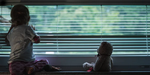 Menina da criança olhando pela janela — Fotografia de Stock