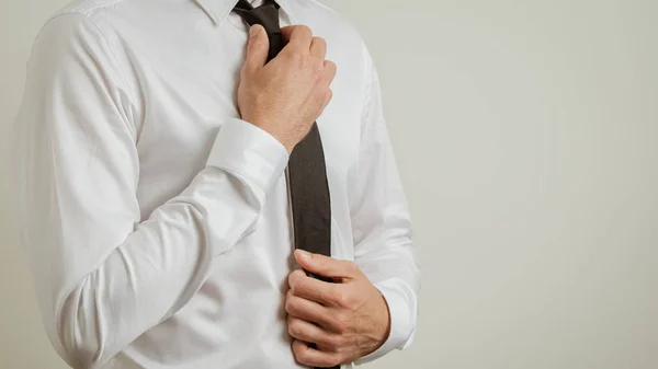 Businessman torso in white elegant shirt tying his black tie — Stock Photo, Image