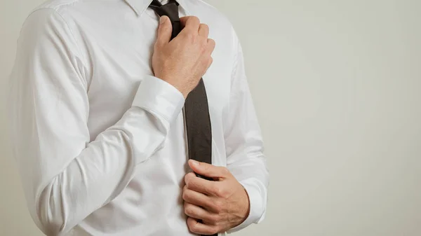 Torso de hombre de negocios en camisa elegante blanca atando su corbata negra —  Fotos de Stock