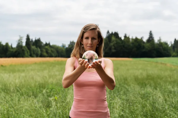 Jonge vrouw mediteren in de natuur houden kristallen bal — Stockfoto