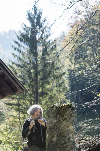 Content senior sculptor carving in stone with  chisel and a mallet, outside on a beautiful sunny day.